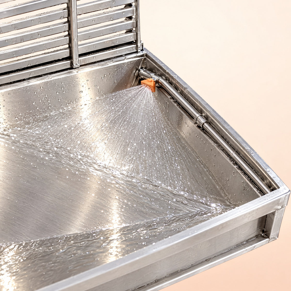 A fan nozzle rinsing the steel pan of the Kiba Rinse