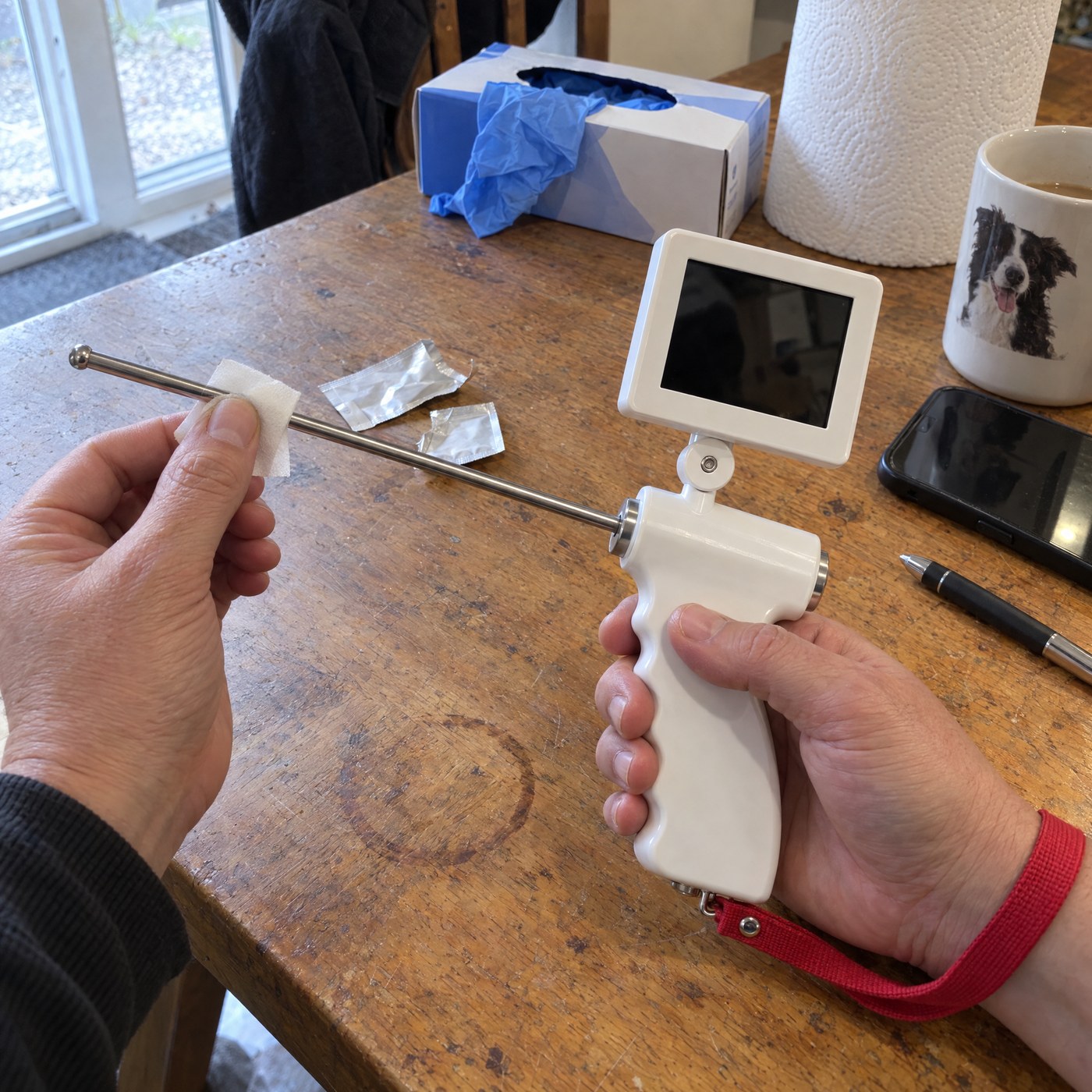 Hands wiping the stainless steel probe of the Kiba Scope with a white swab