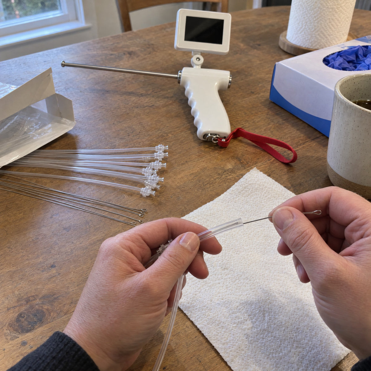 Hands sliding a looped steel guide wire into a clear insemination tube